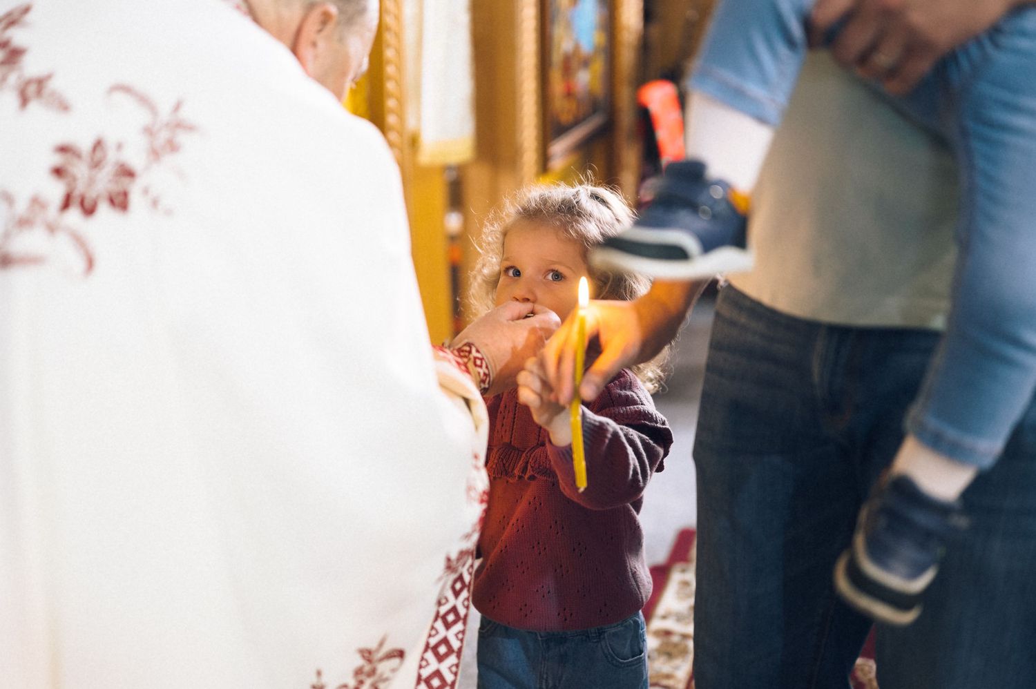 Young child reaching out to receive communion from a priest during a religious ceremony in a church.