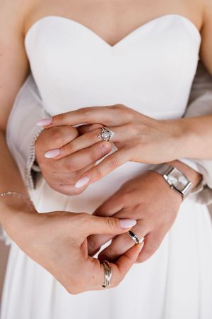 Close-up of newlyweds hands showing diamond engagement ring and wedding bands after ceremony.