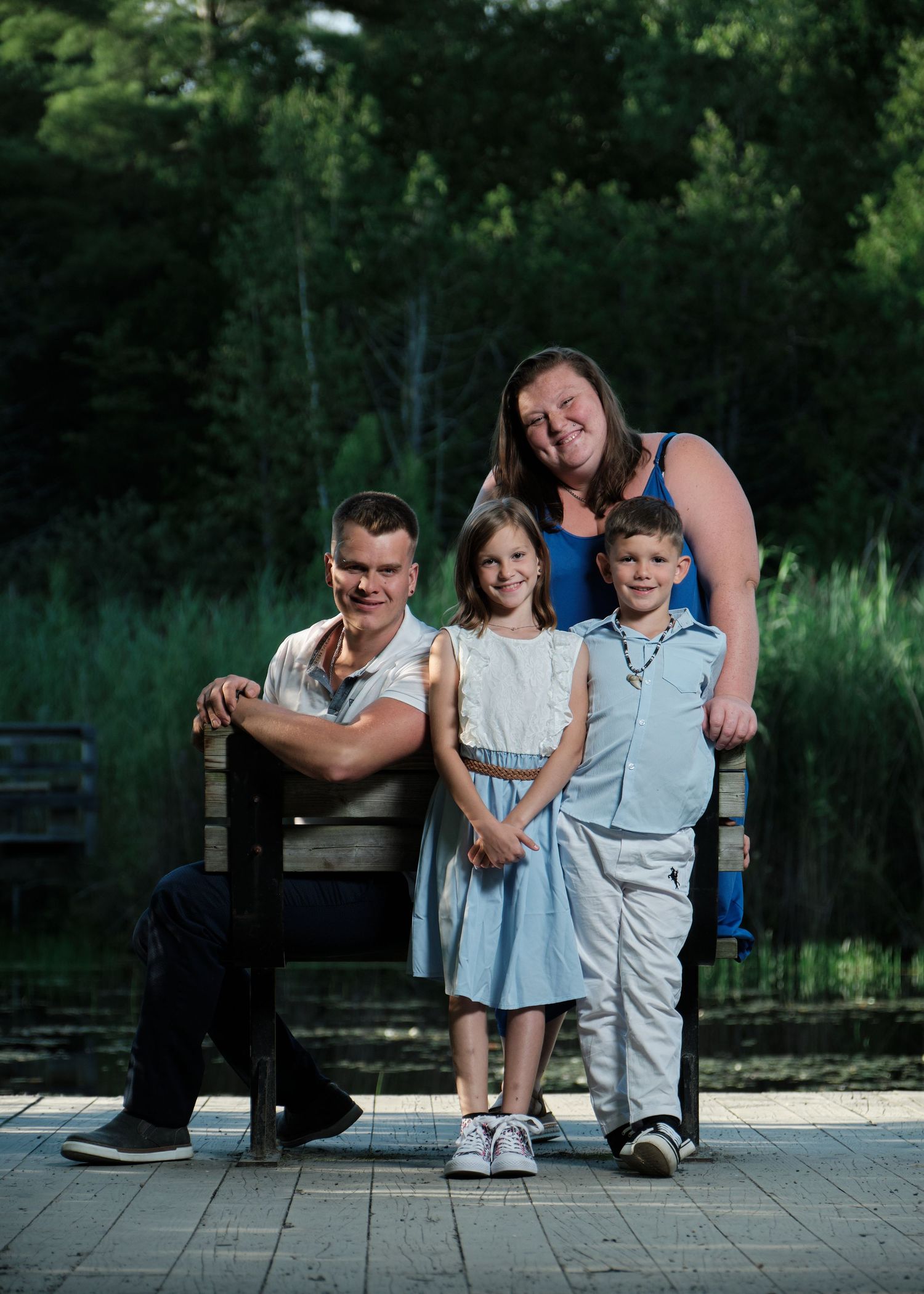Une famille réunie autour d'un banc de parc, près d'un étang.