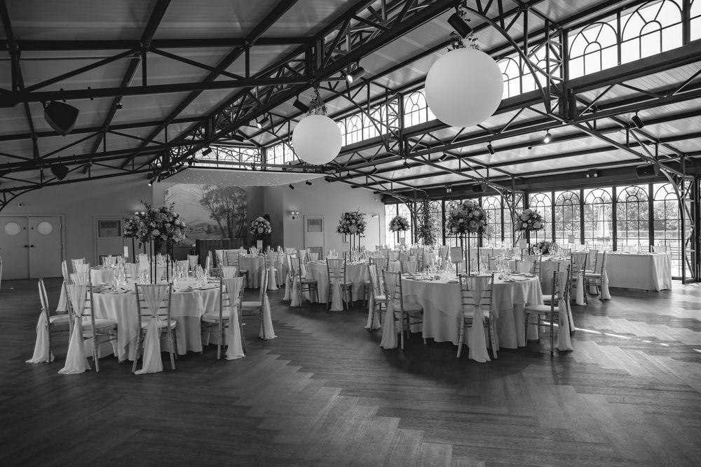 Elegant black and white wedding reception hall with round tables, chiavari chairs, and large balloon ceiling decorations.
