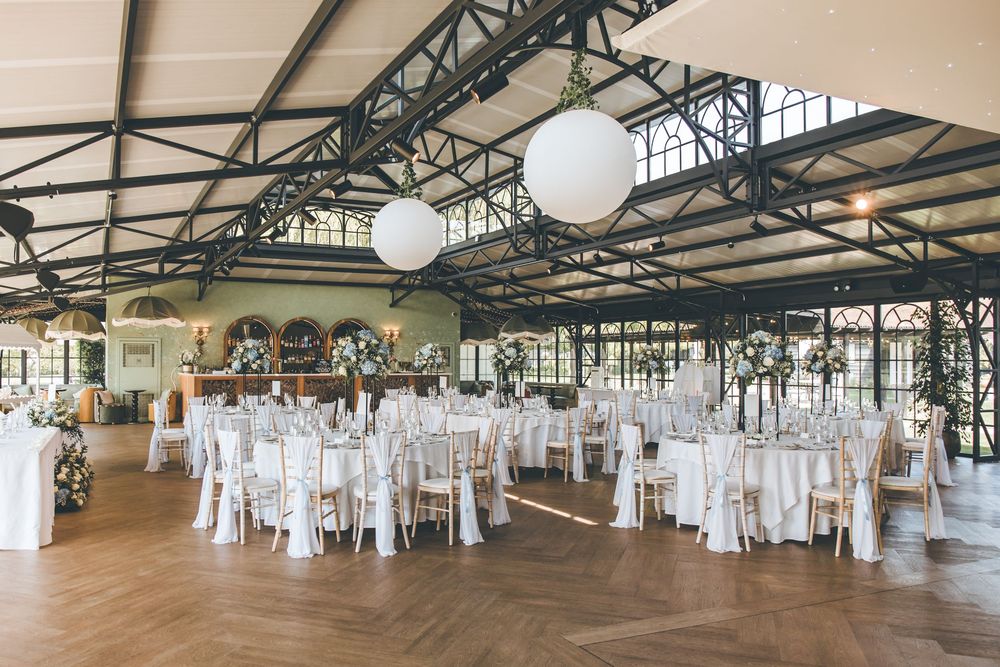 Elegant wedding reception hall with white chairs, round tables, and globe pendant lights.