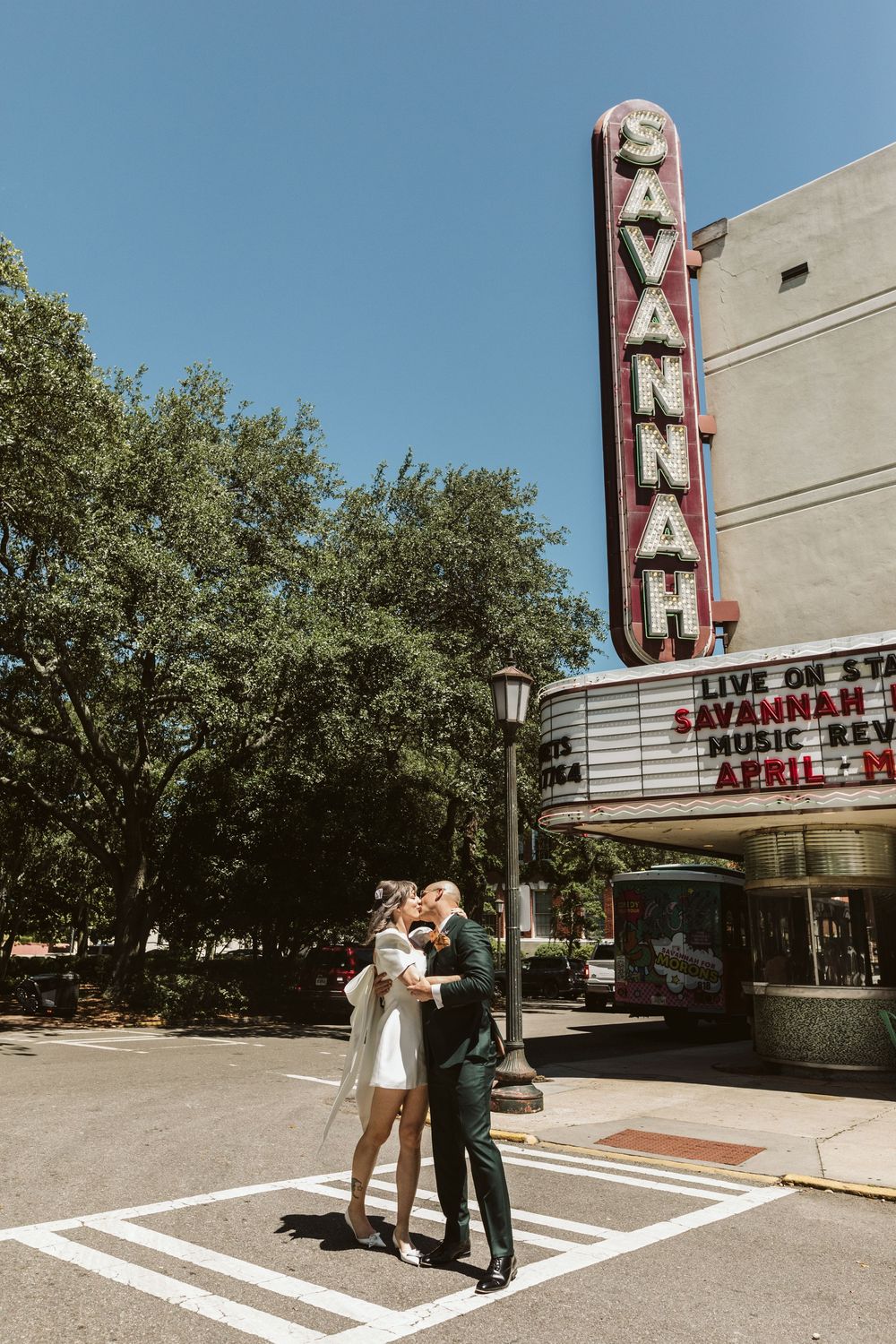 Couple kissing in front of the iconic Savannah Theatre marquee sign on a sunny day in Savannah, Georgia.