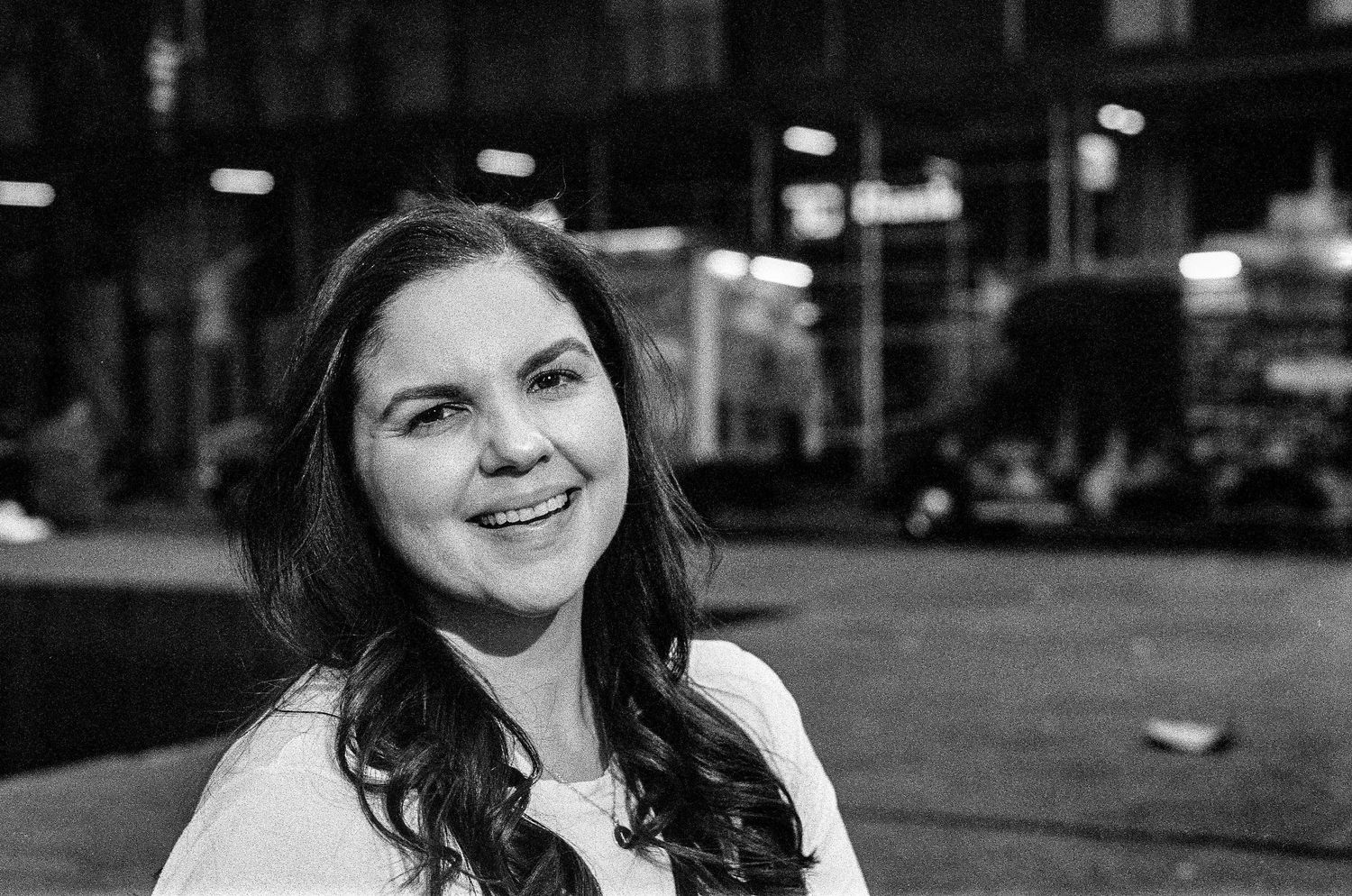 Black and white portrait of person smiling outdoors at night.