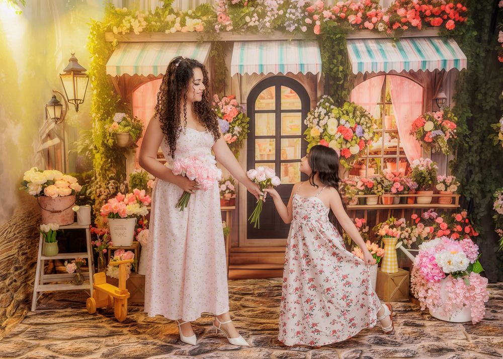 Woman and young girl in floral dresses share a sweet moment in a colorful flower shop backdrop.