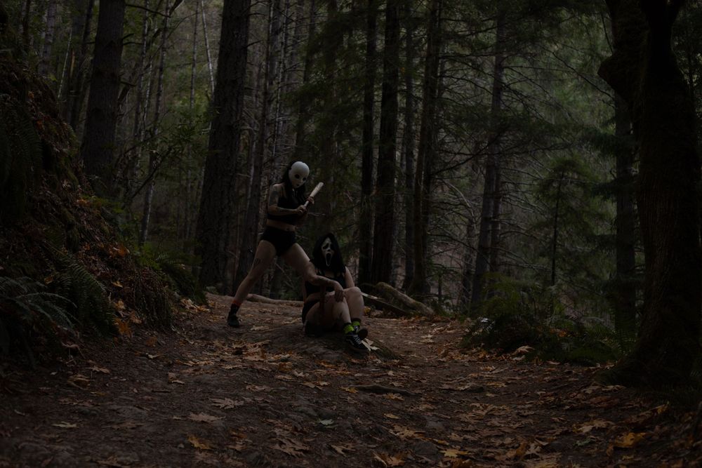 Dramatic scene of figures in masks on a misty woodland path.