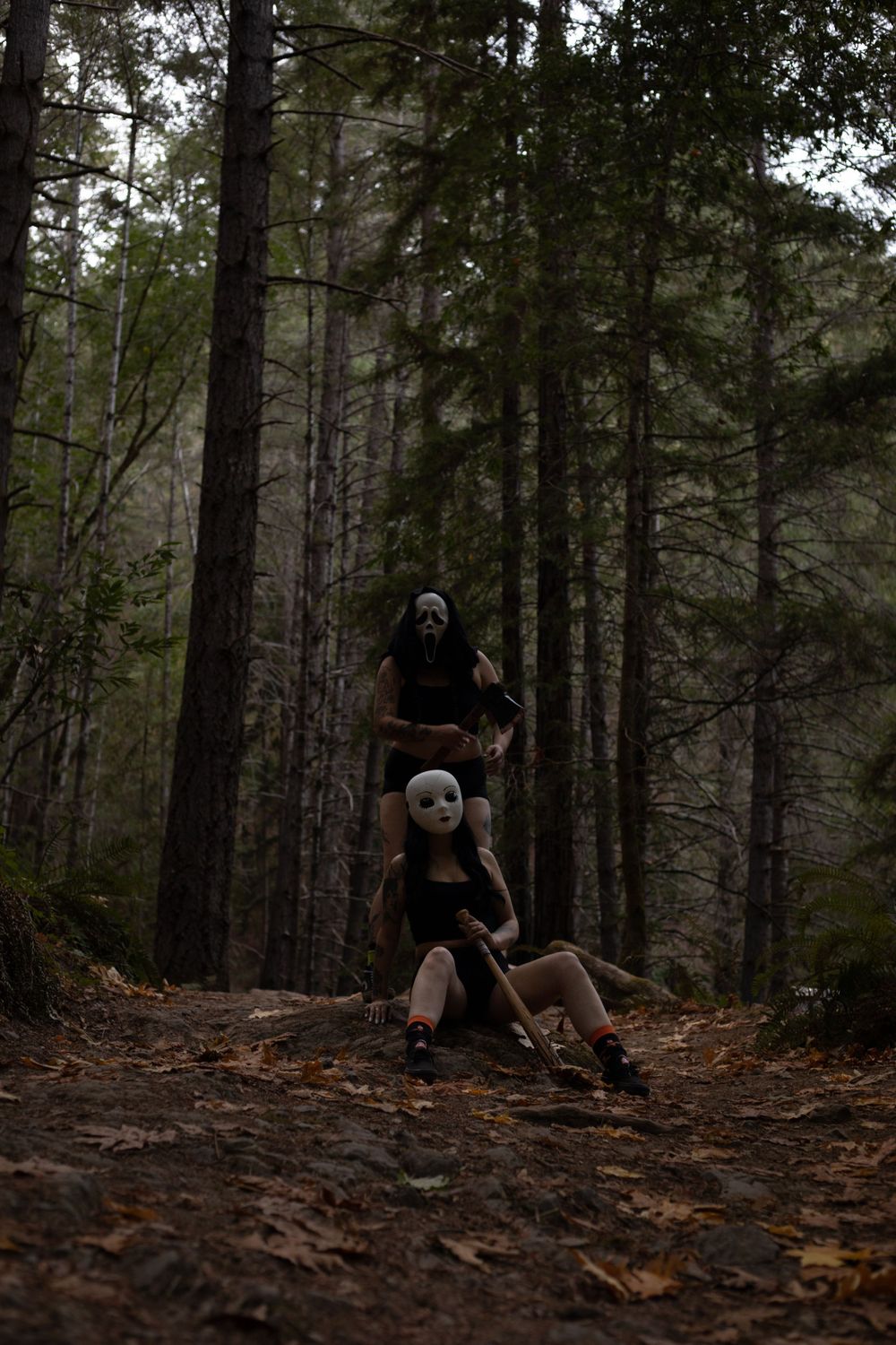Atmospheric forest photo with masked figures creating an eerie scene among tall trees.