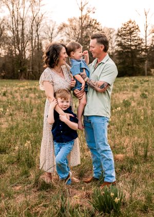 A loving family shares a joyful moment together in a serene field during golden hour sunset.
