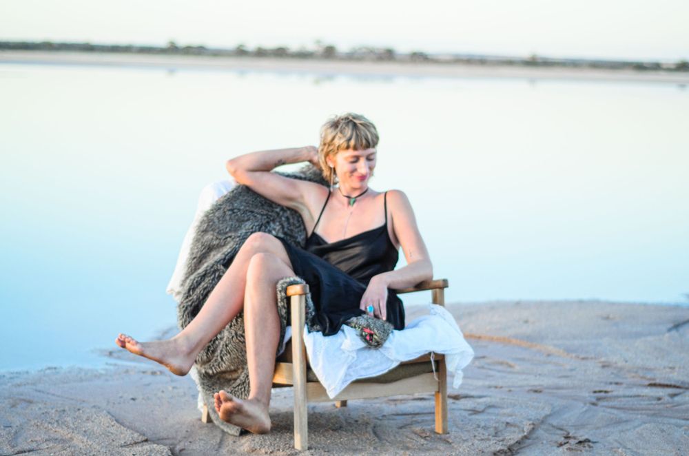 Retro-styled photograph of person relaxing in beach chair by waterfront.