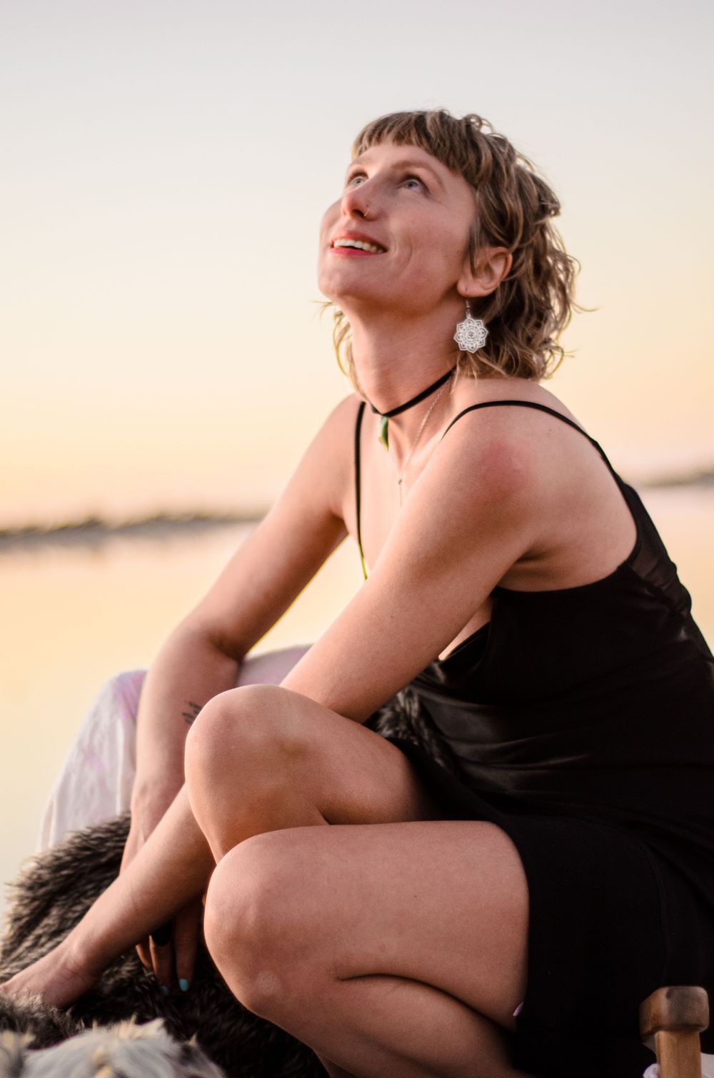 Person in black dress sitting outdoors during golden hour sunset.