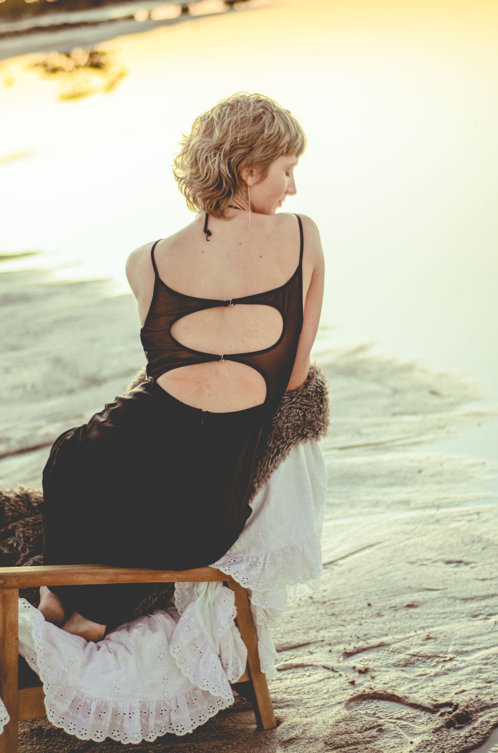 Back view of black dress with cutout details and lace on beach setting.