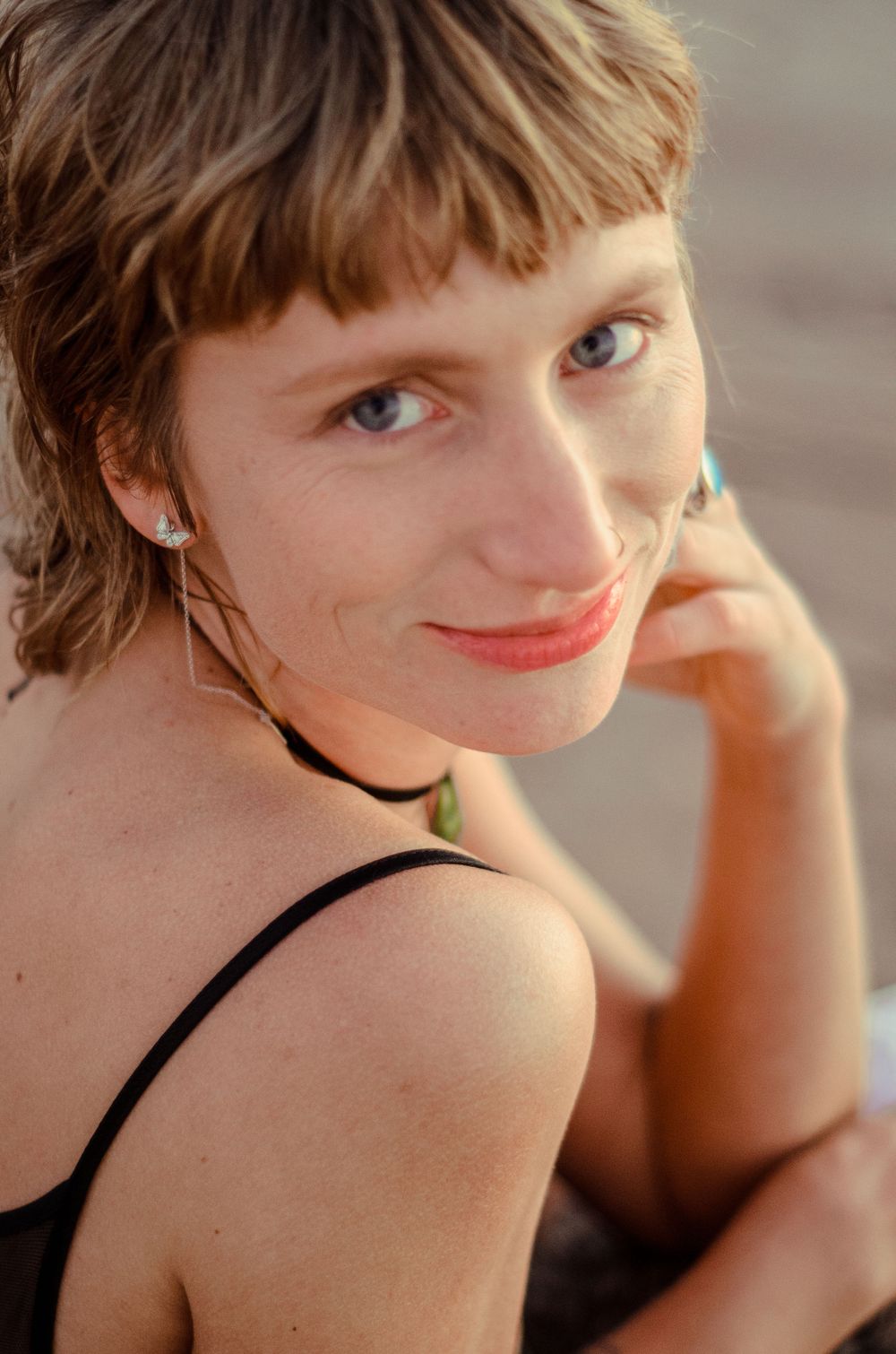 Warm-toned portrait with black choker necklace and natural makeup.