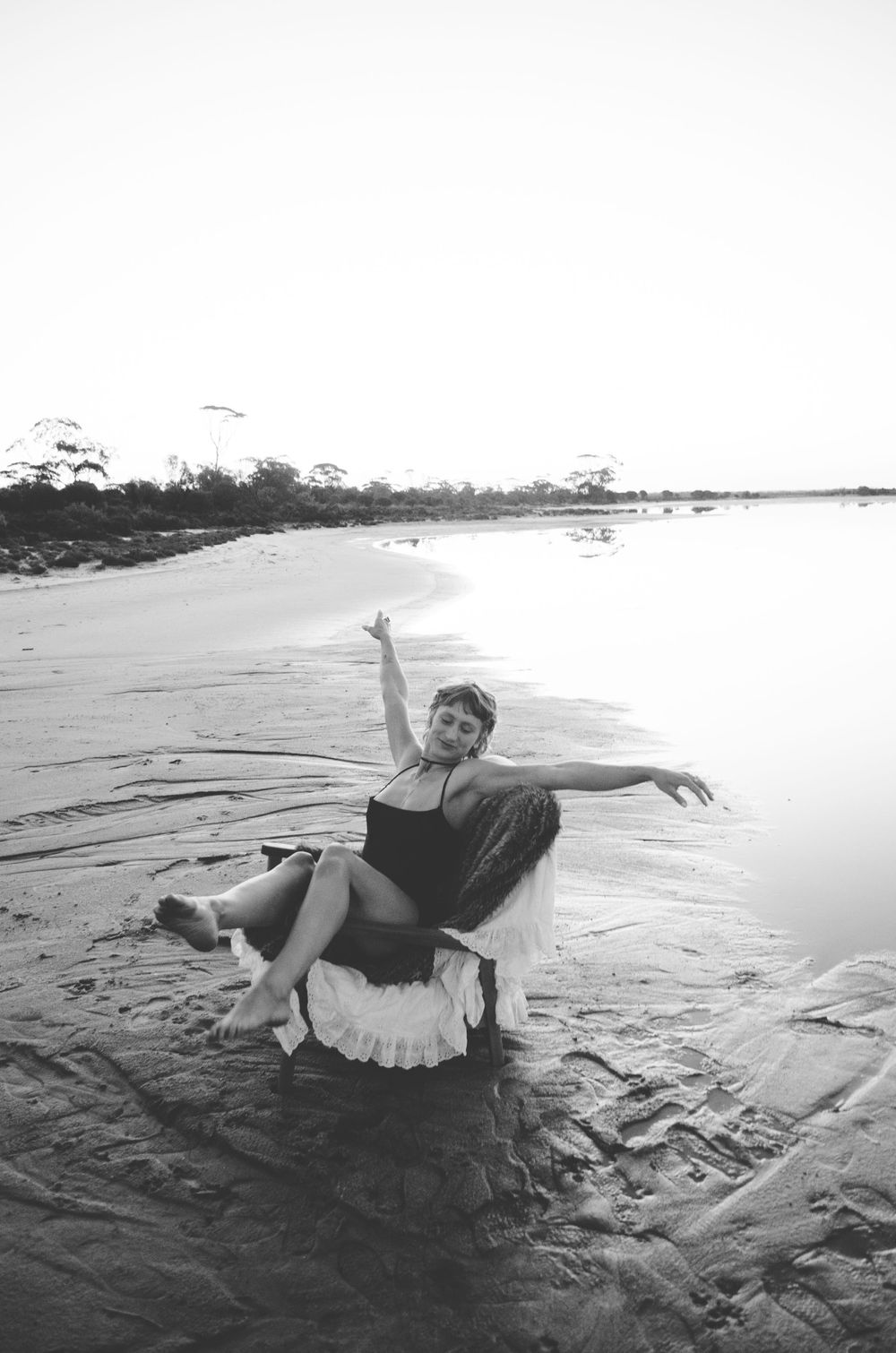 Black and white beach scene with vintage-style dress and dramatic pose.