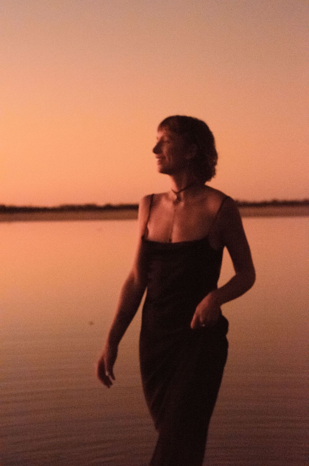 Ethereal sunset portrait of a dancer by tranquil waters in warm golden light.