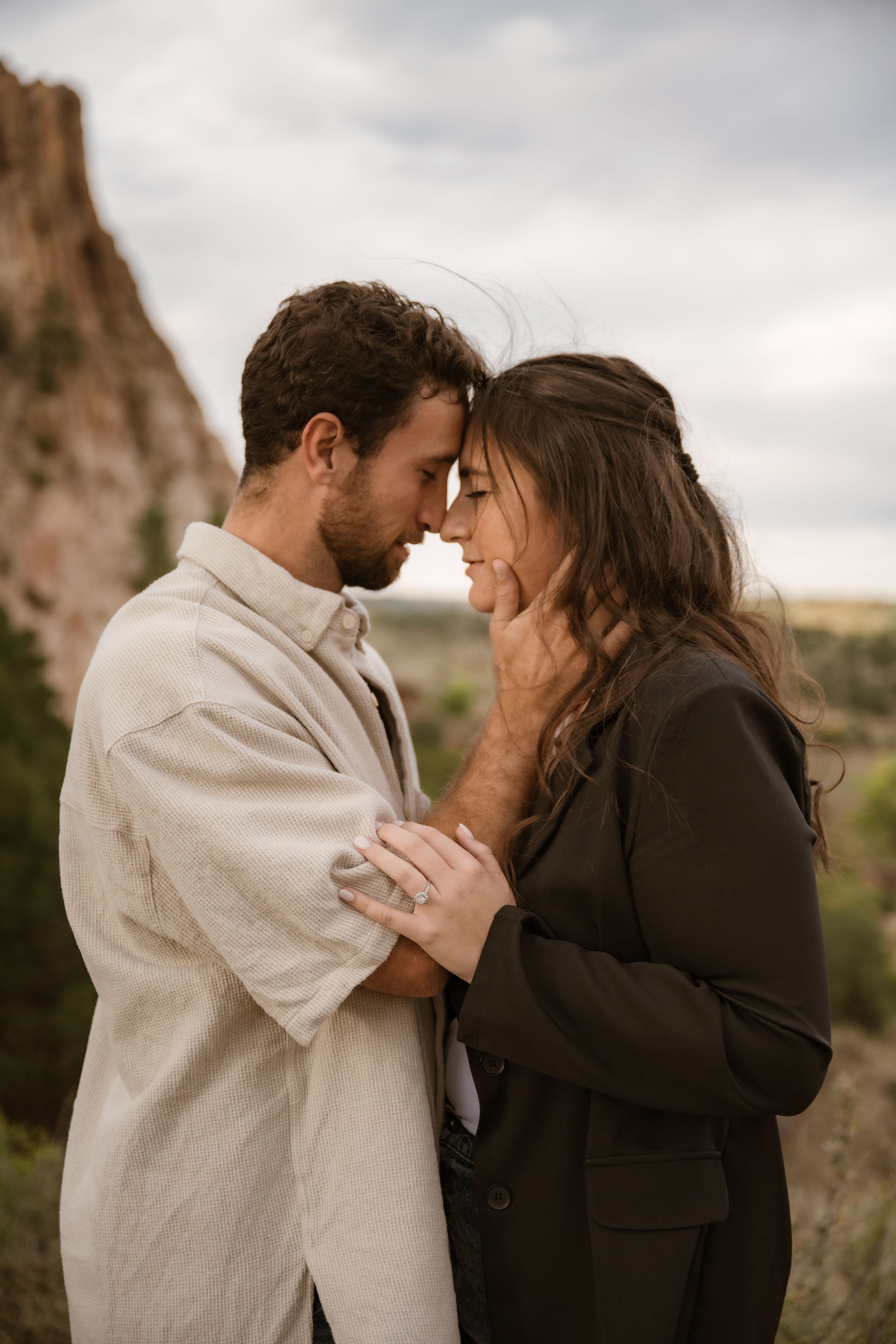 An intimate moment is captured between two people with desert rock formations behind them.