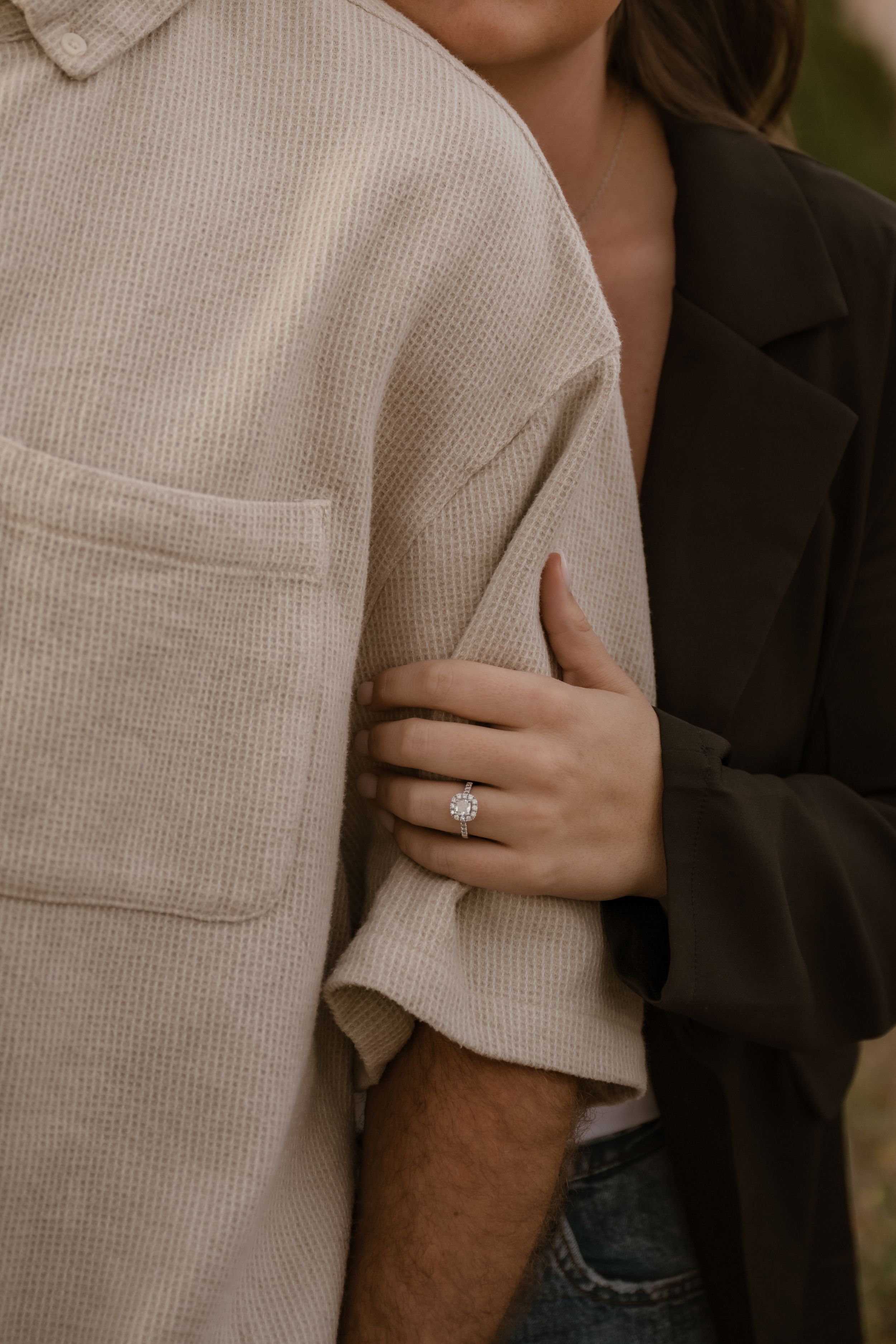 Close-up shot showing details of an engagement ring and intimate embrace.