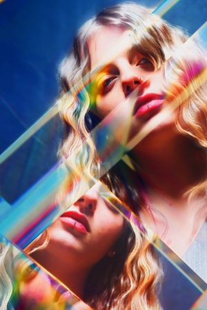 Artistic triple portrait with rainbow prism effects and vibrant colors on blue background.