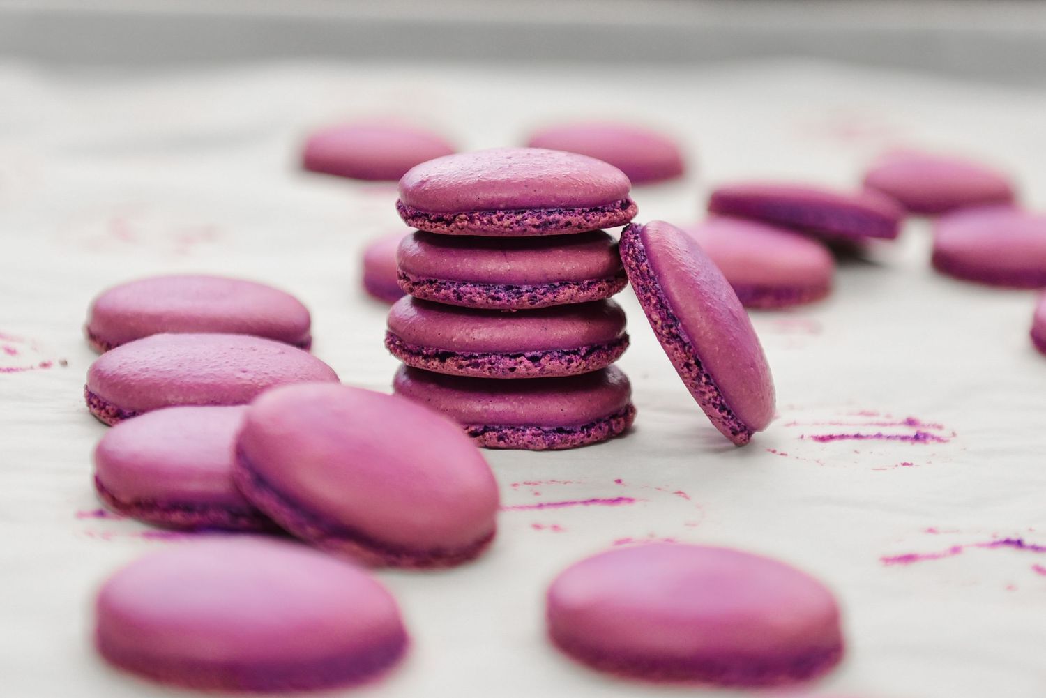 Purple macarons arranged on a light surface with dark chocolate filling.