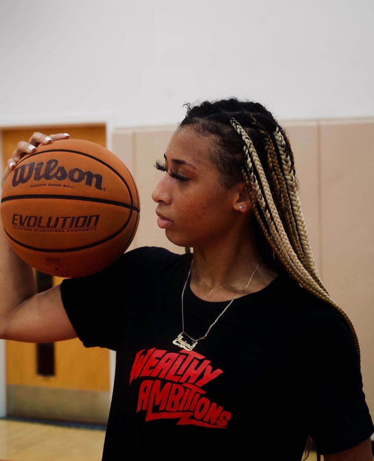 Basketball player with braided hair holding Wilson Evolution basketball.