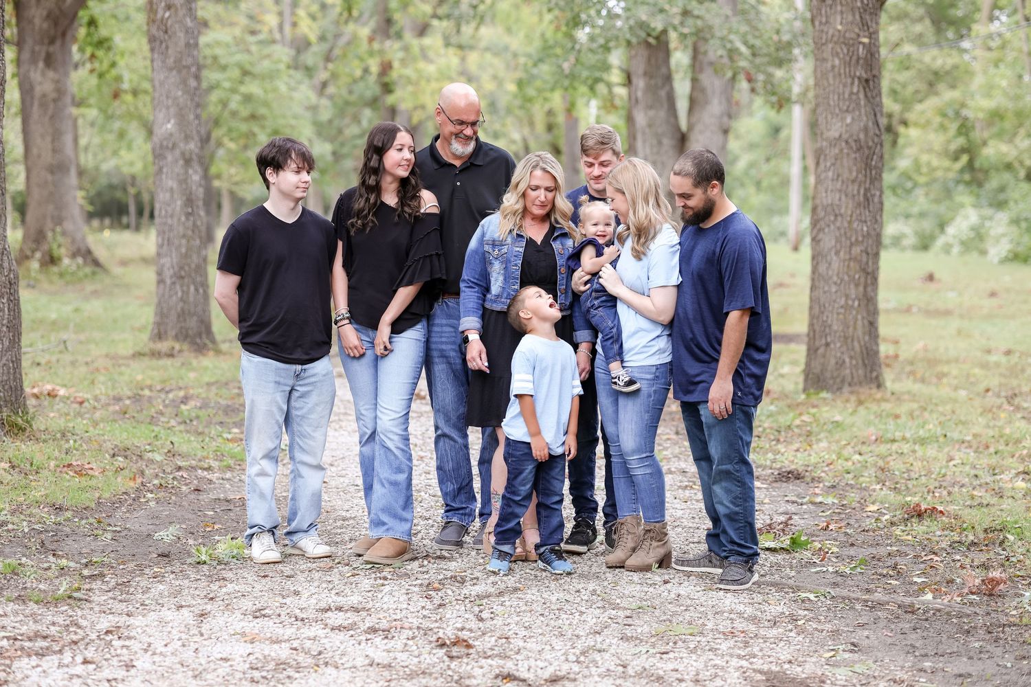 Family of 11 stand together and share a fun moment together on a trail with trees