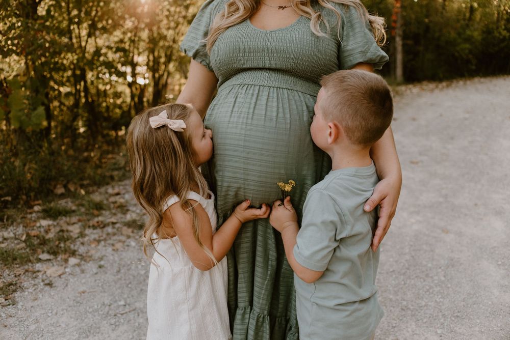 Maternity photo session featuring family embracing on outdoor path at golden hour.