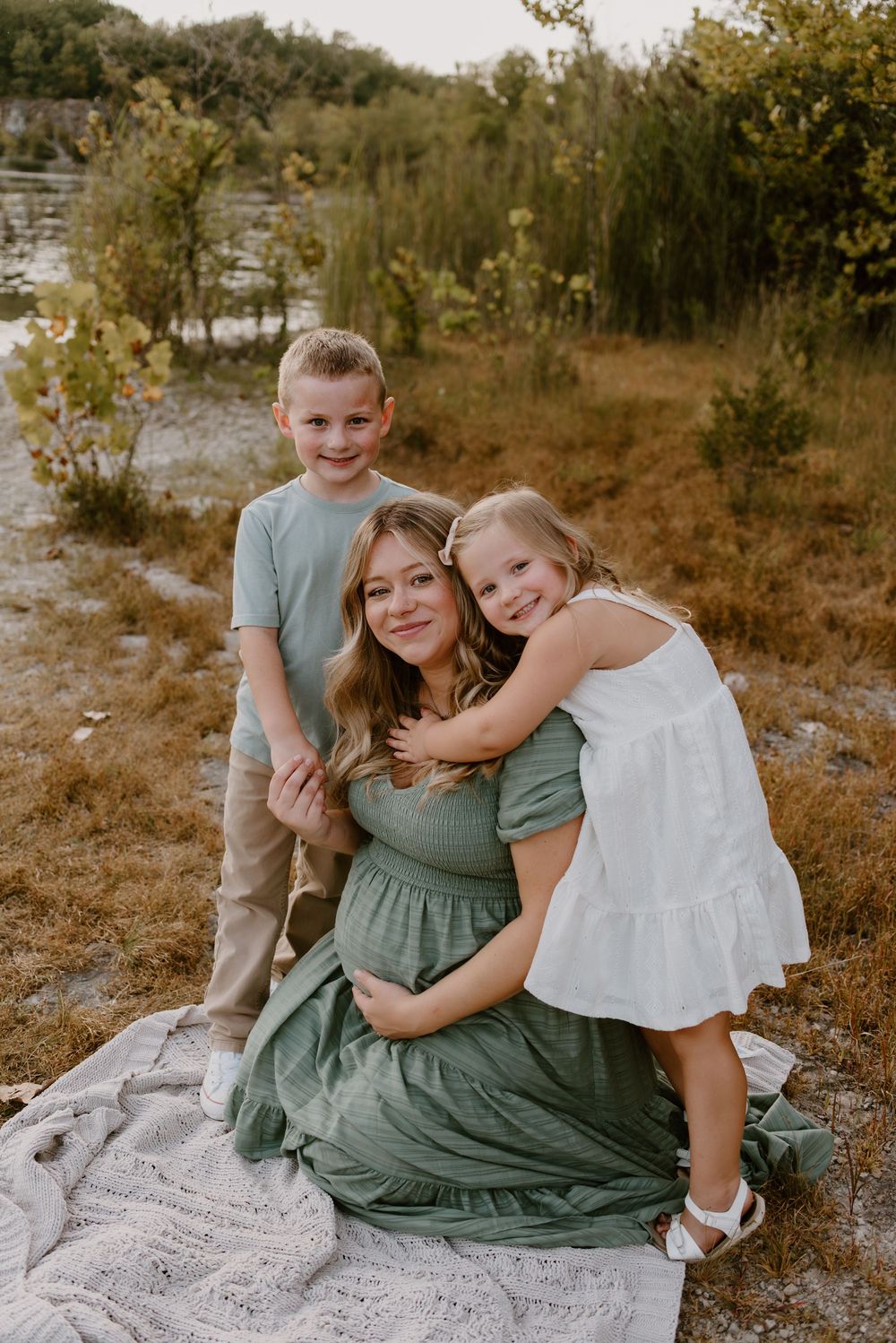 Outdoor family portrait session on a white blanket during golden hour.