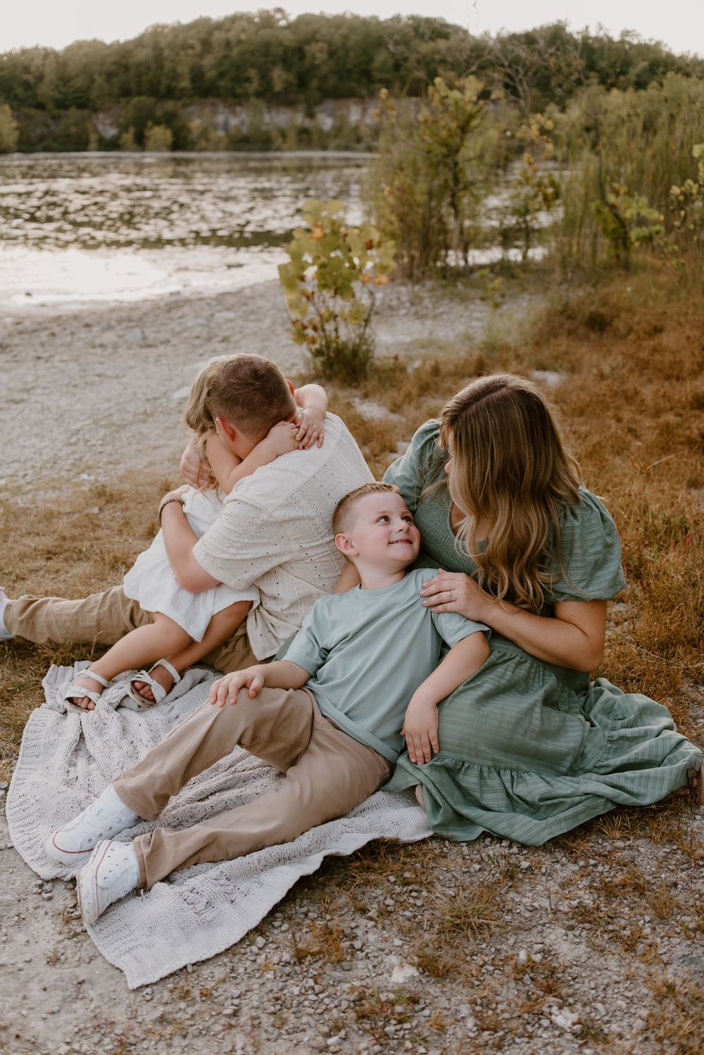 Family lying together on a blanket outdoors during a lifestyle photoshoot.
