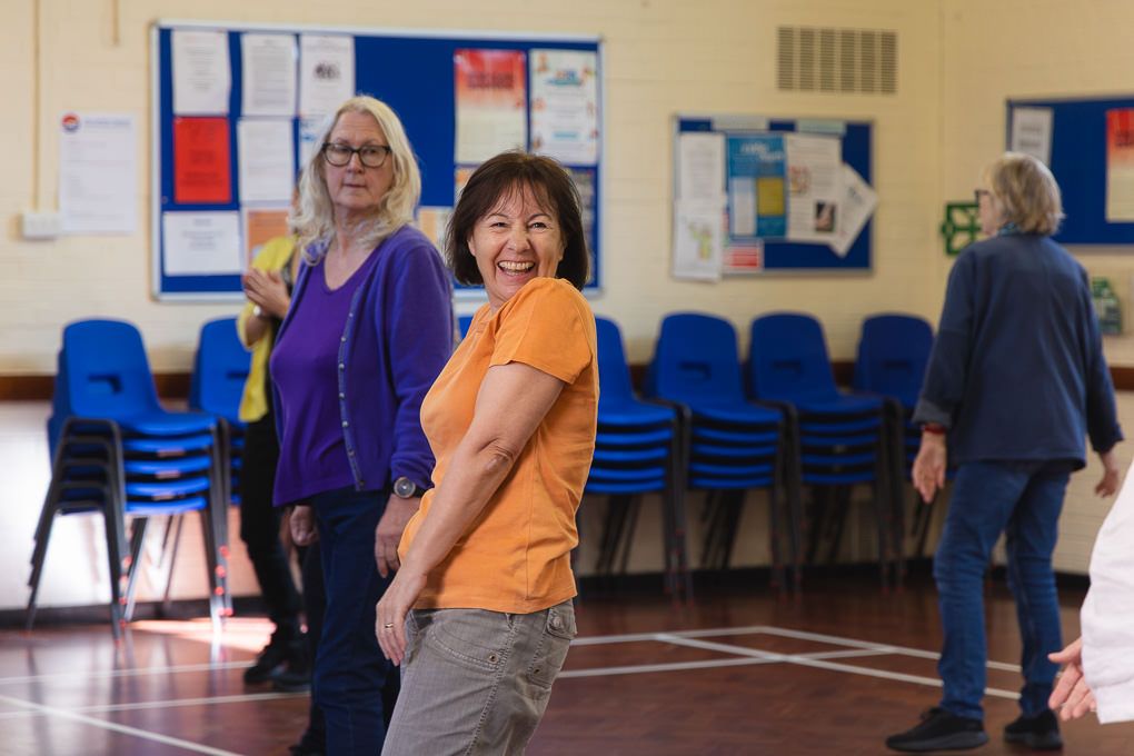 People participate in a line dancing class inside a Letchworth community centre gymnasium.