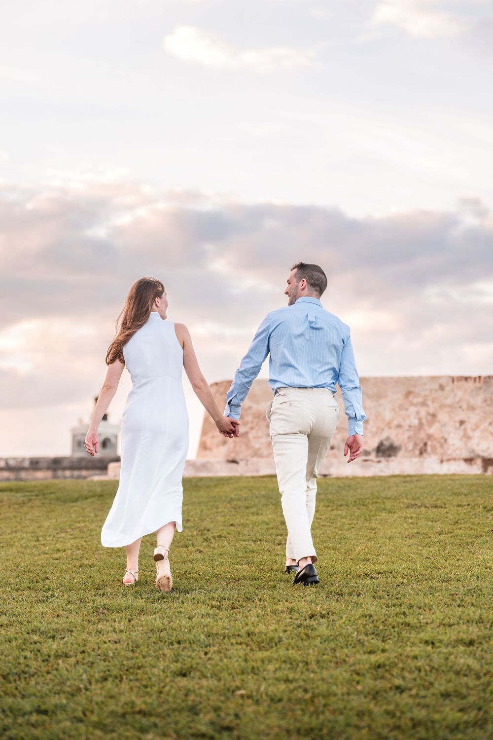 Couple holding hands on grassy field during engagement session in San Juan Puerto Rico