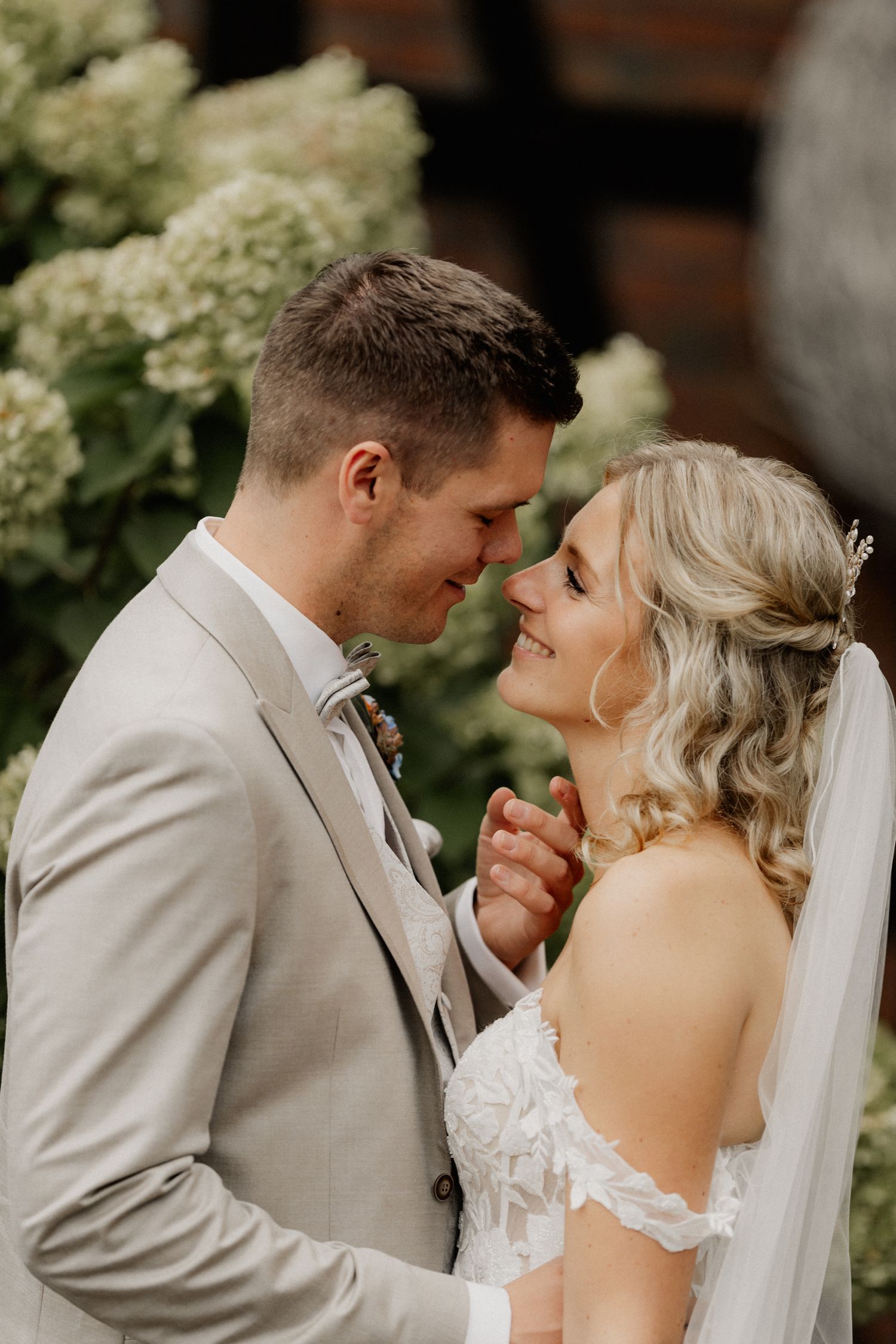 Intimate moment between newlyweds sharing a tender embrace outdoors.