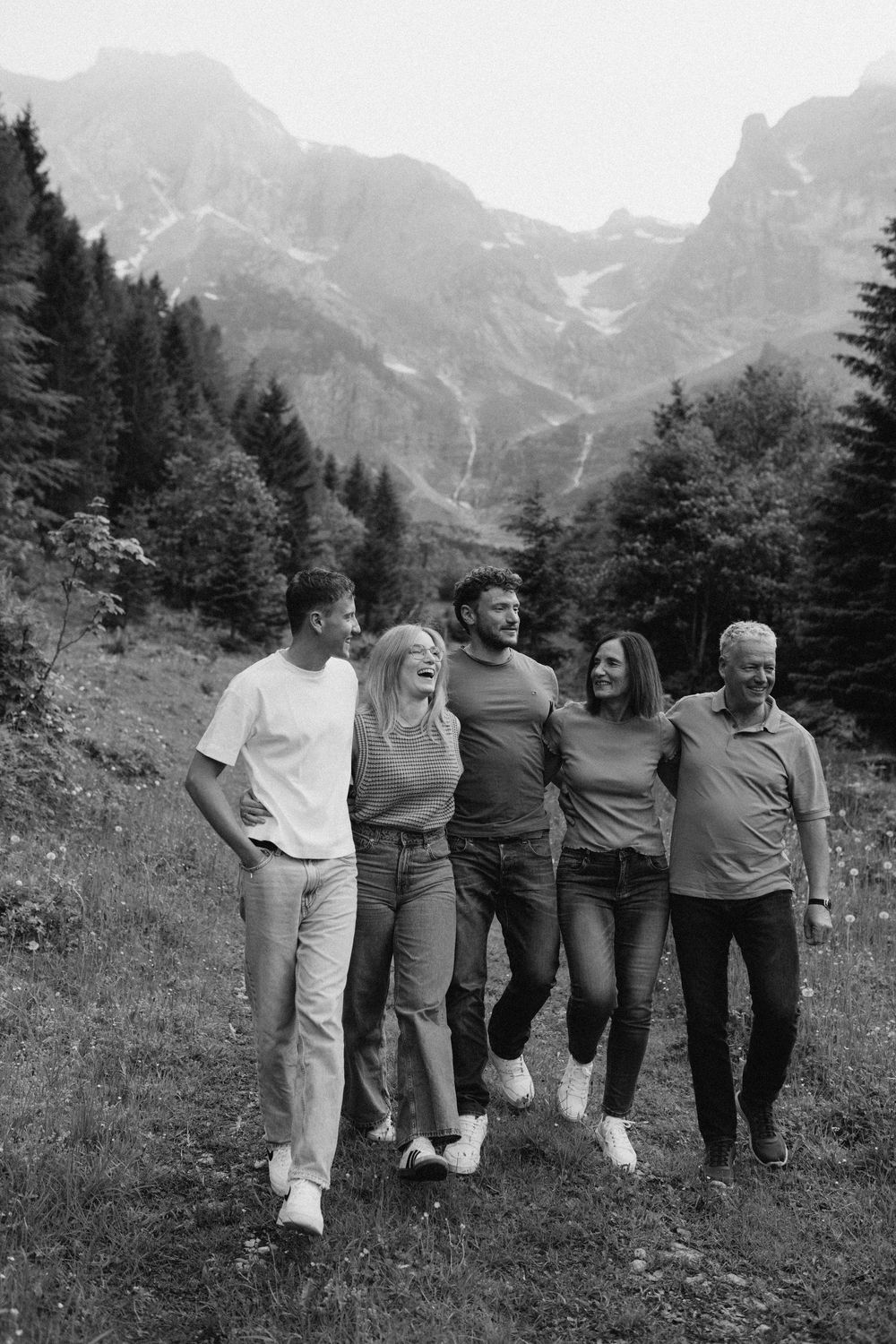 Group photo series in black and white showing people posing together in front of mountain peaks.