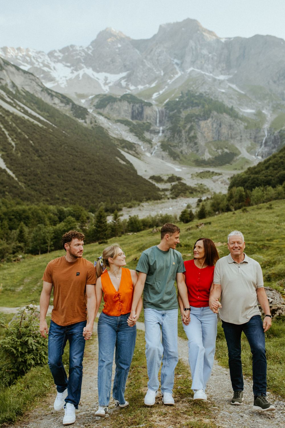 Friends hiking together on a mountain path surrounded by majestic alpine scenery.