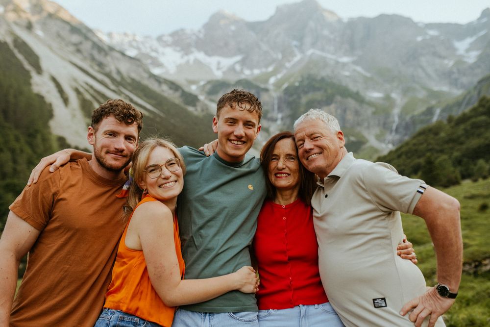 Group embracing while enjoying a mountain adventure with snow-capped peaks in the distance.