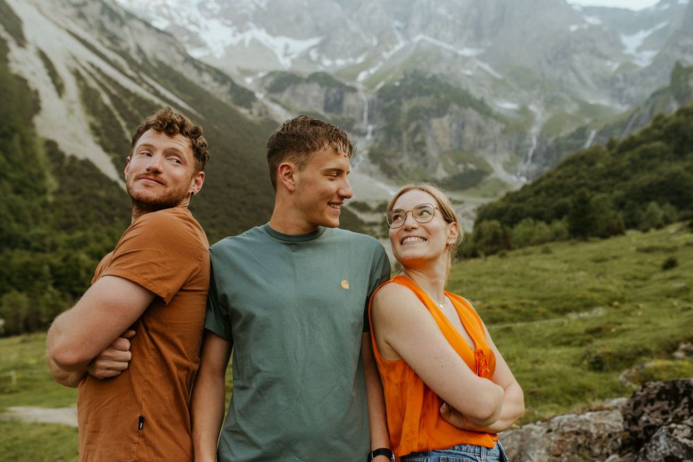 Friends sharing laughter and embraces against a backdrop of dramatic mountain landscapes.