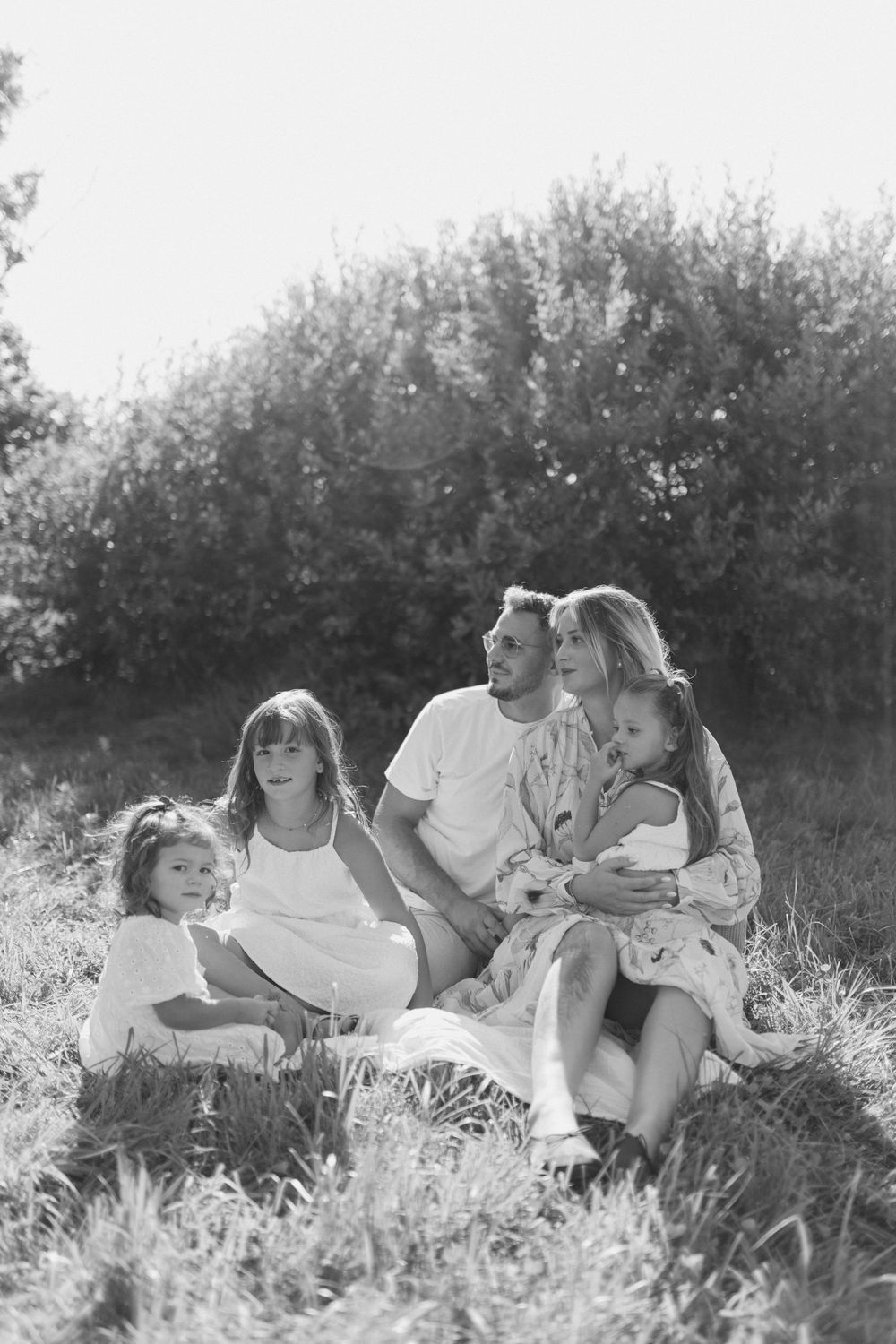 A series of black and white photos showing a family relaxing together in a grassy meadow.