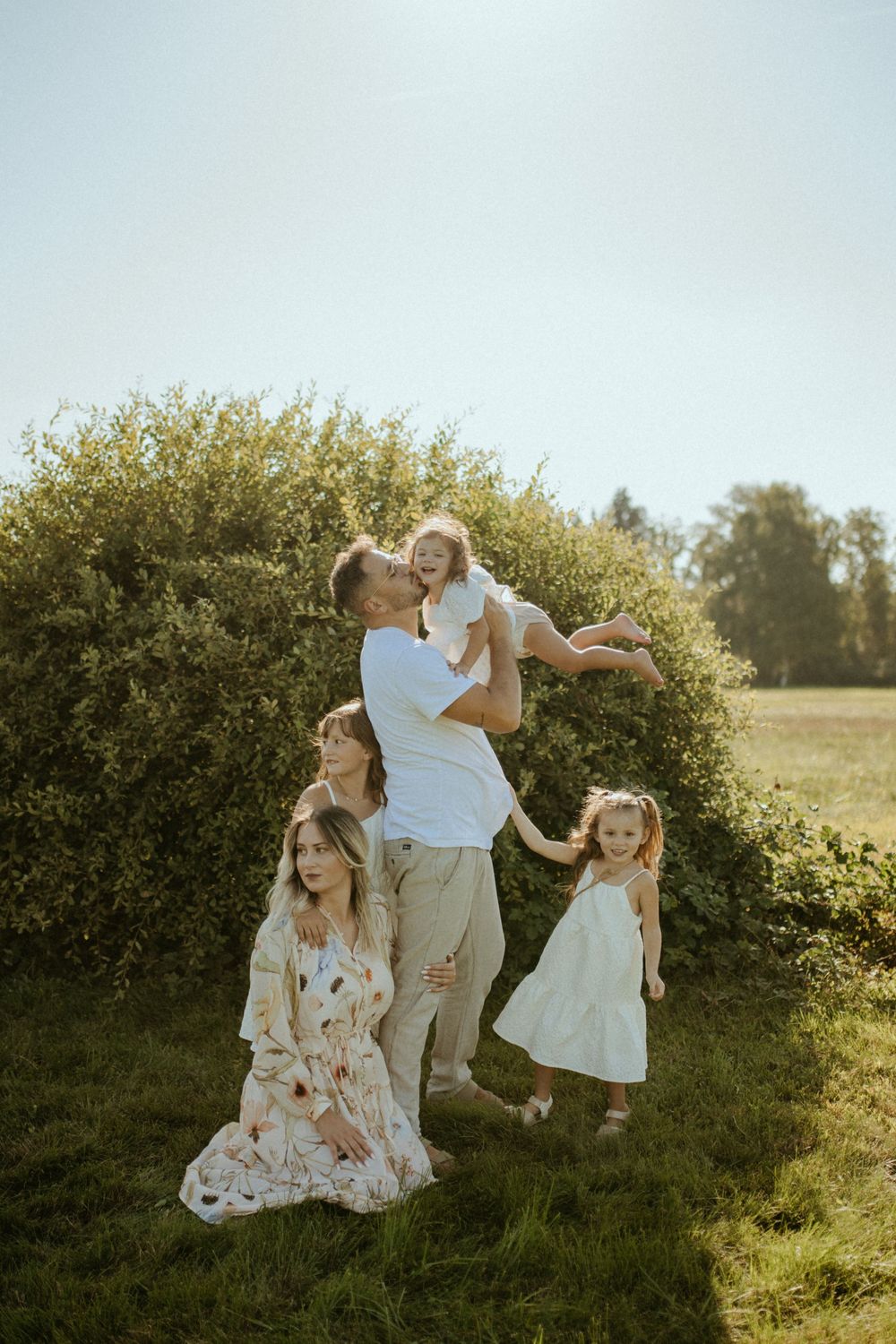A family enjoying a playful moment together on a sunny hillside with golden light.