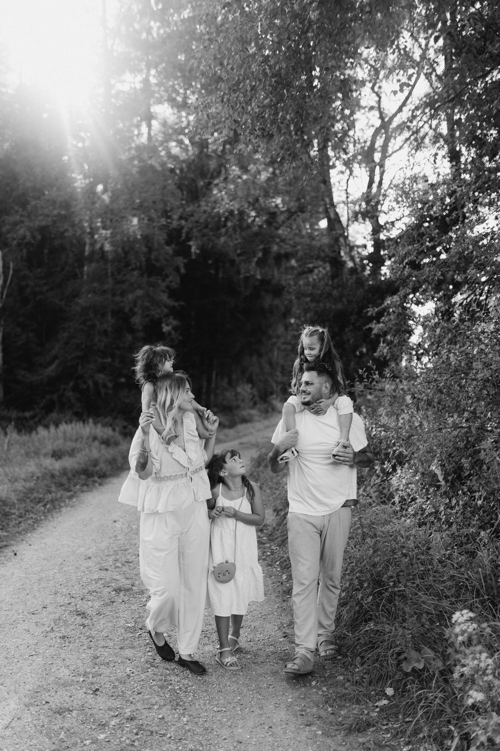 Black and white photos of a family strolling along a sunlit path through bushes.