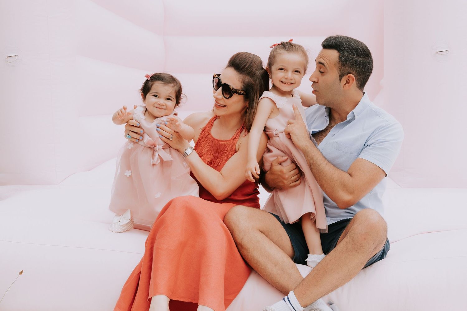 Family lounging together on white couch in casual home setting.