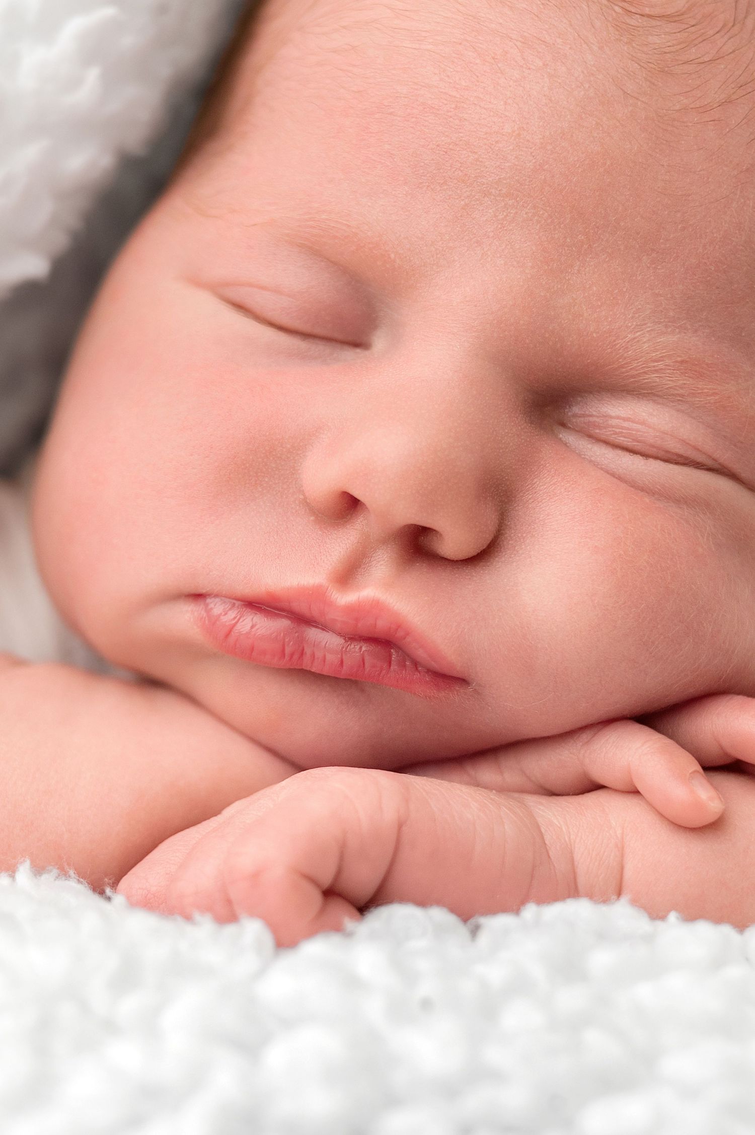 Baby wearing yellow headband and hooded outfit gazes at camera with bright eyes and sweet expression.