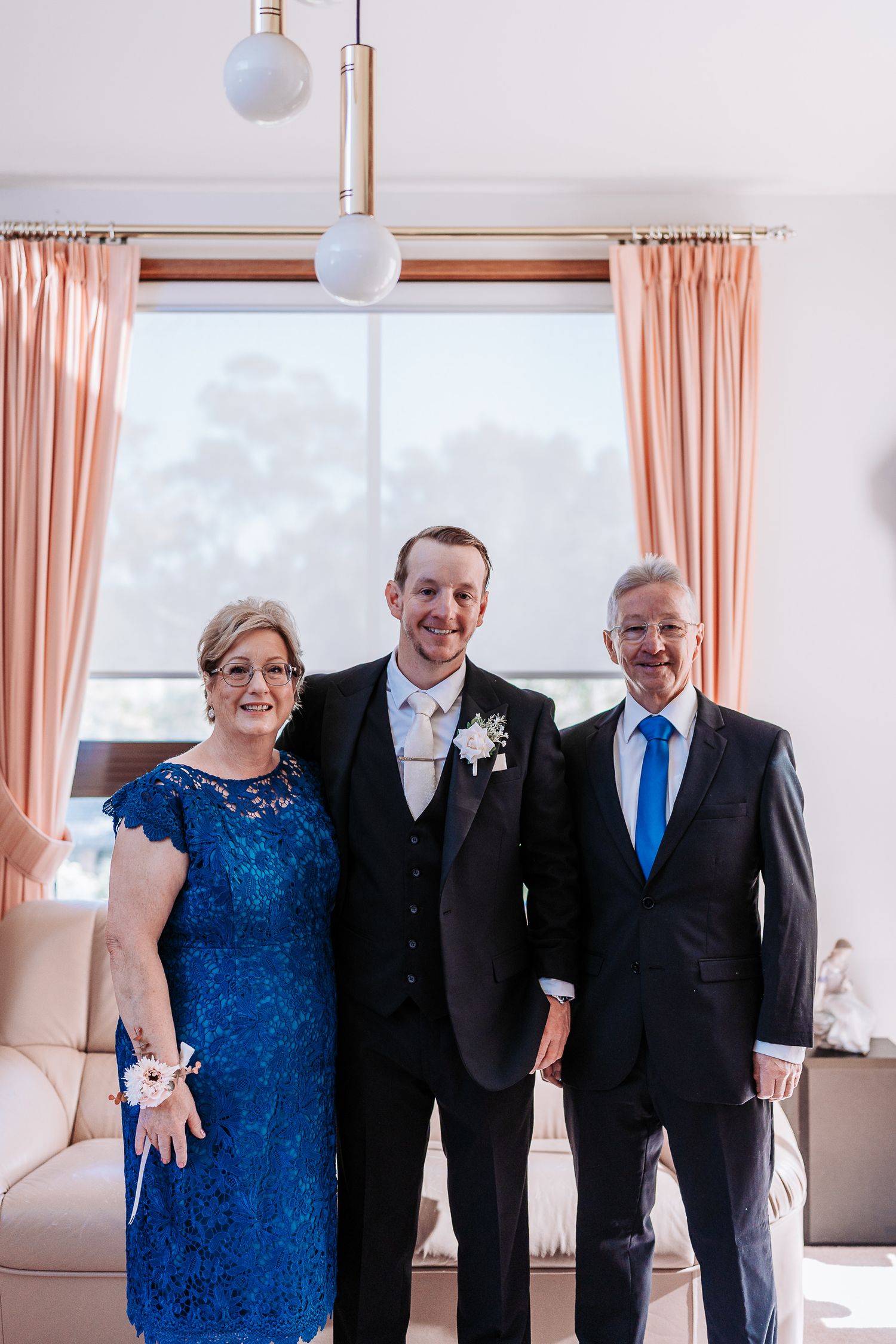 Formal group photo showing people in elegant attire including a blue dress and black suits at an indoor event.