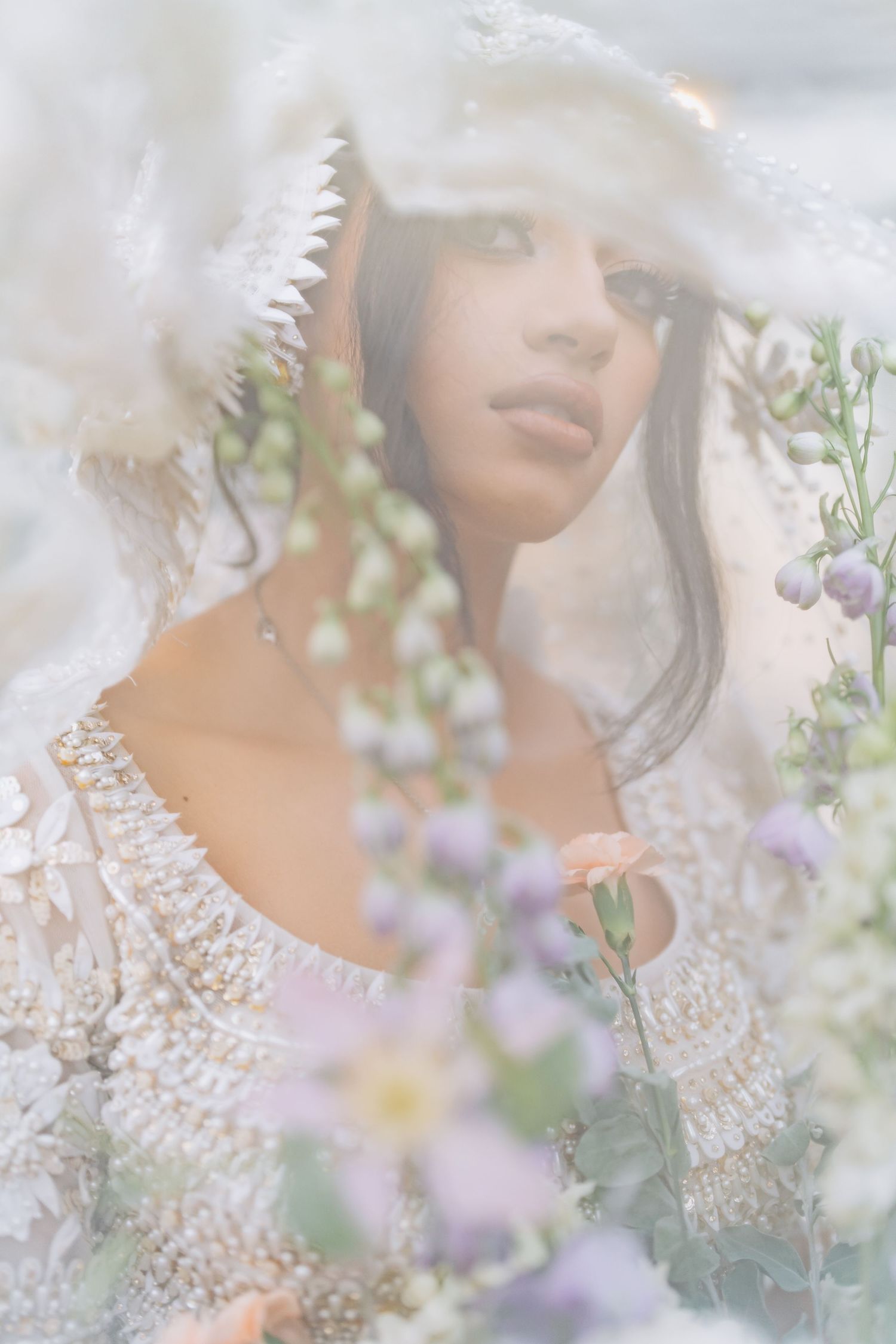Delicate lace details and flowers create a dreamy bridal portrait through a sheer veil.