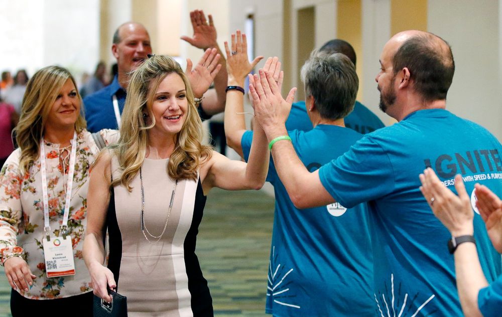 People high-five and celebrate during an energetic business conference or training session.