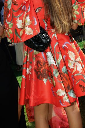 A group wearing matching bright red floral dresses standing together at an outdoor event.