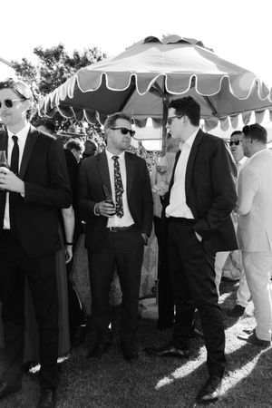 A group mingles under white canopy tents at an elegant outdoor gathering.