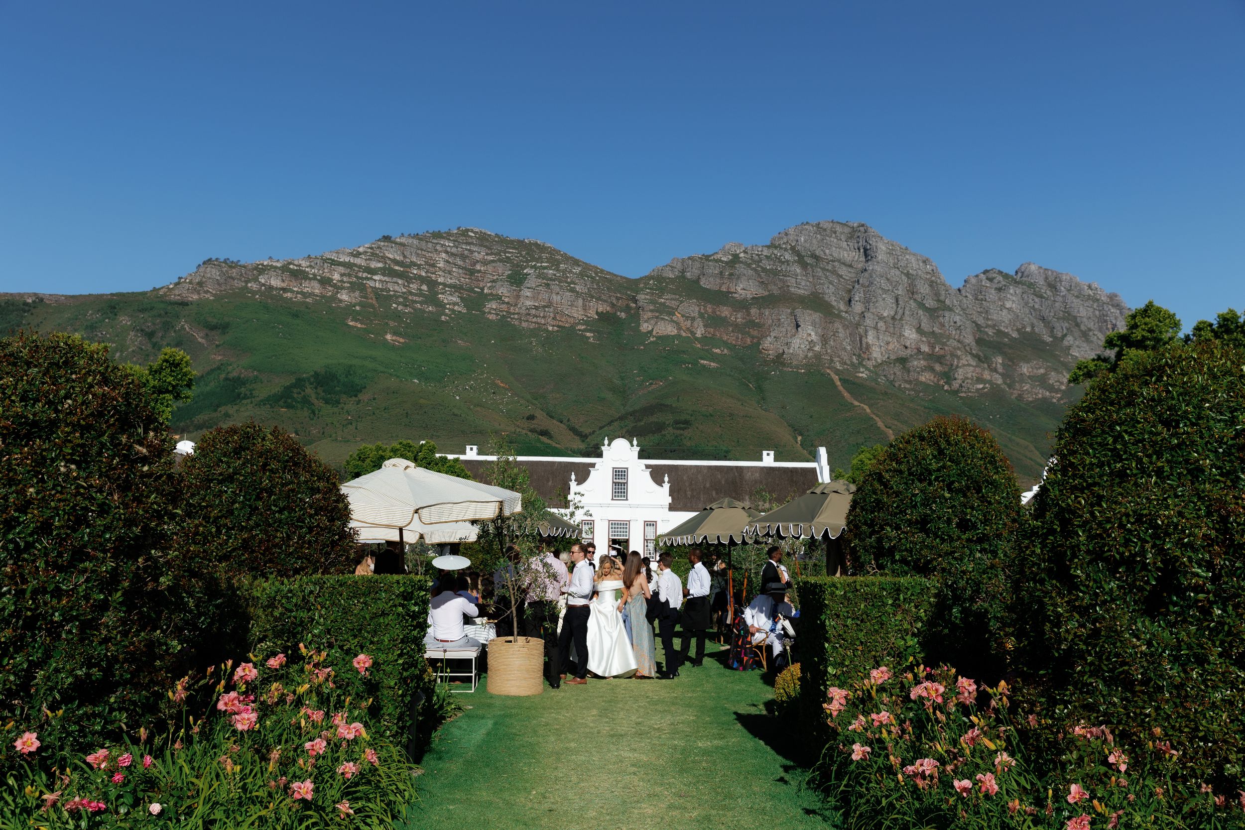 Scenic mountain landscape with white buildings nestled among lush greenery against a clear blue sky.