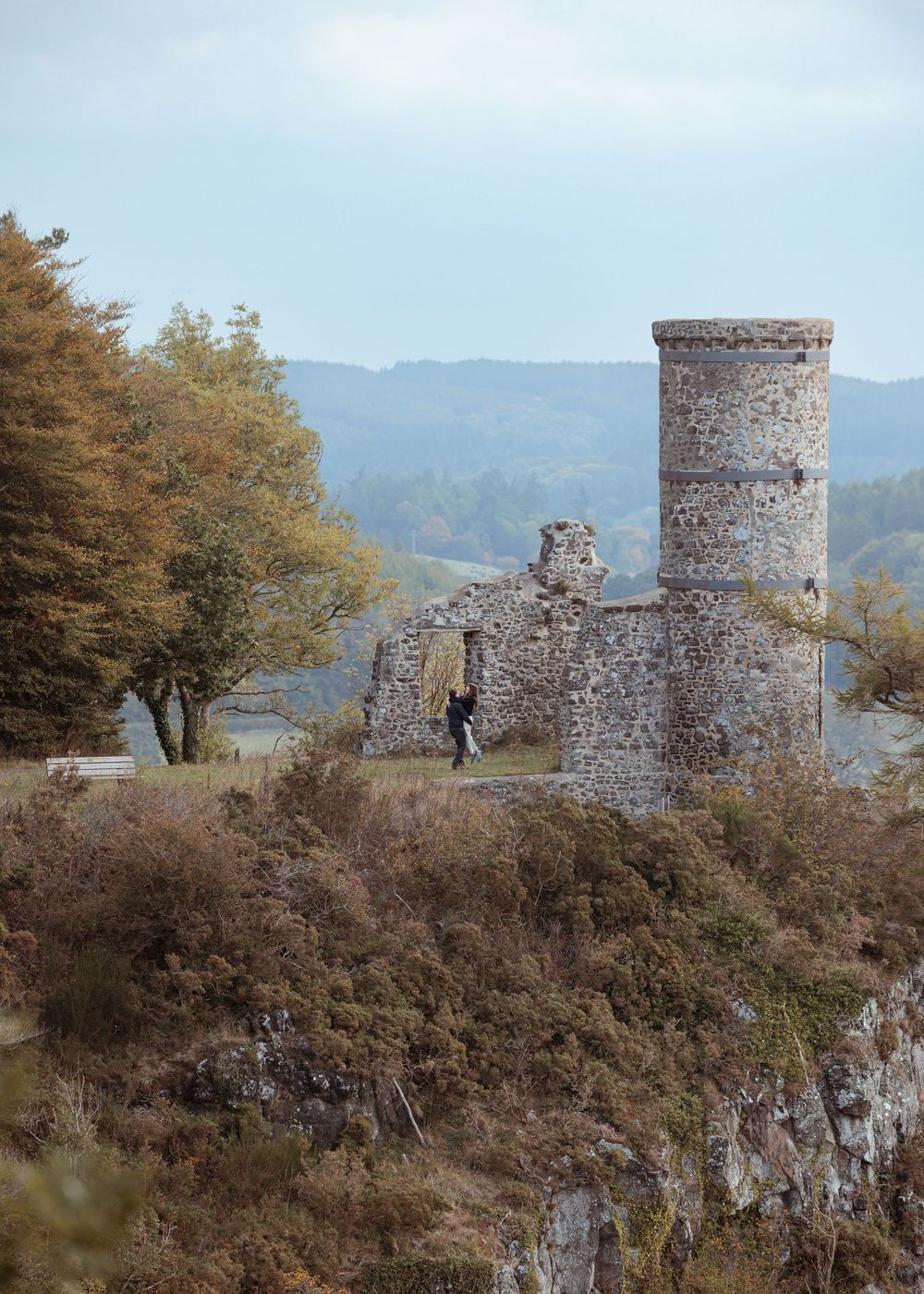 Ancient stone watchtowers stand atop a rugged hillside overlooking a scenic mountain landscape.