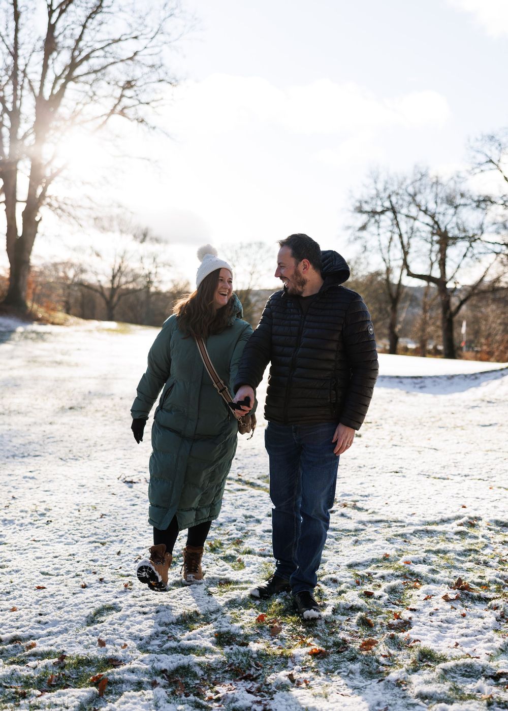 Two people walking together on a snow-covered path through a winter landscape at sunset.