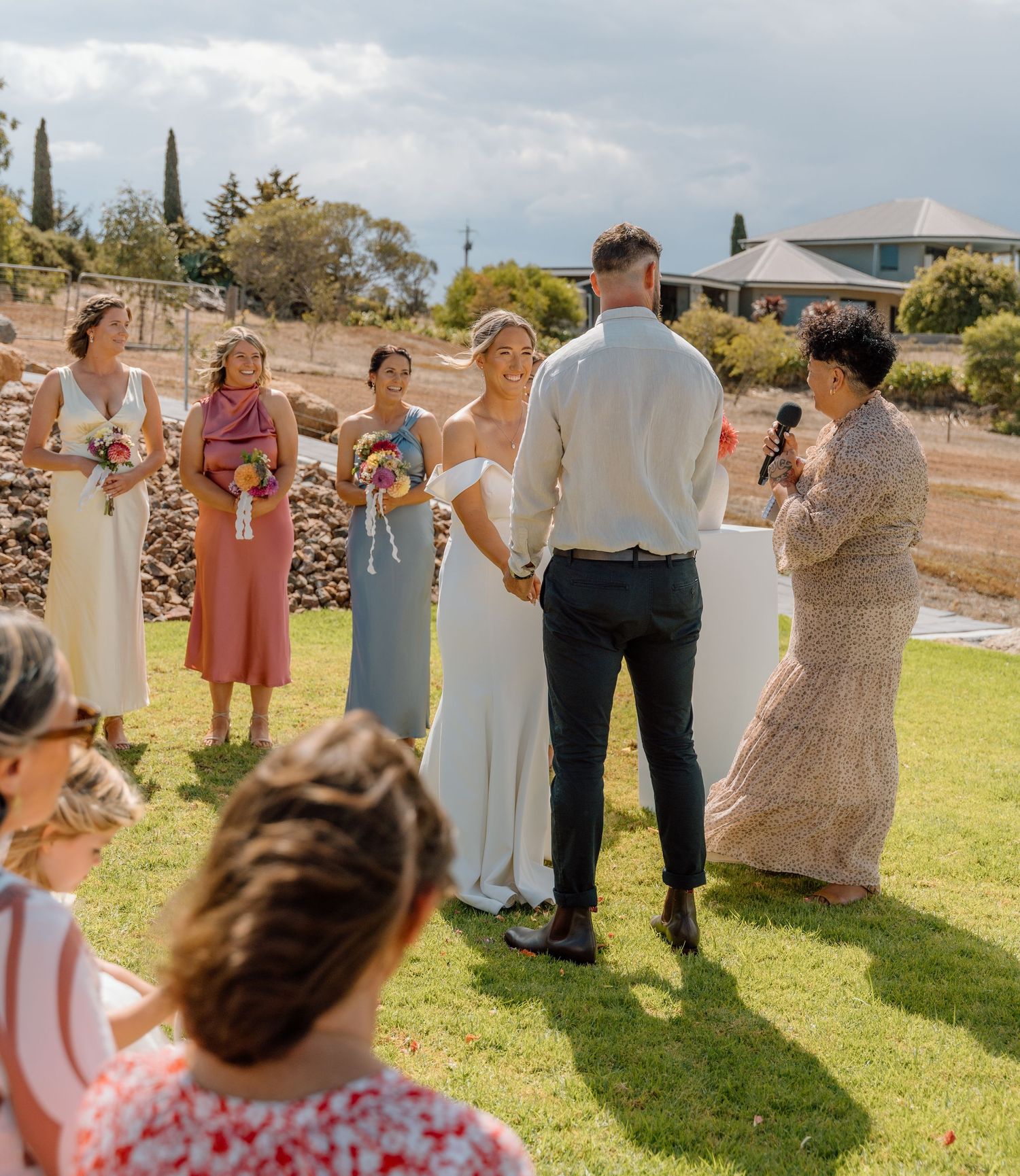 Wedding guests gather on a sunny lawn for a celebratory outdoor reception with drinks and conversation.