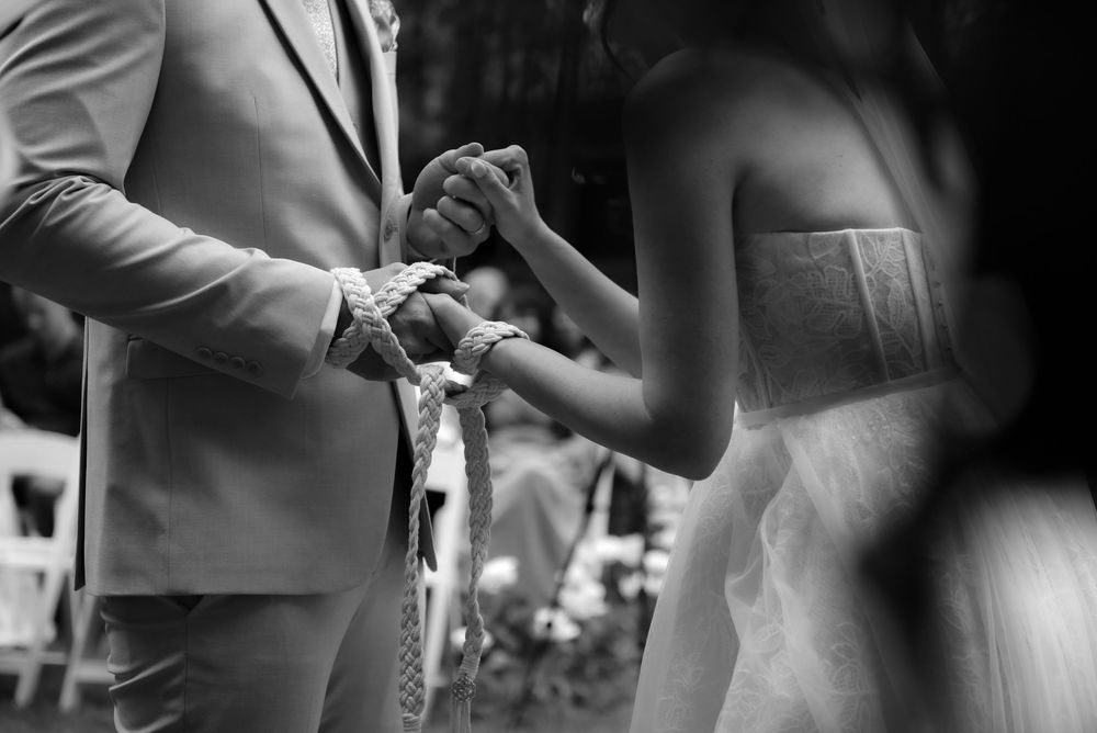 A black and white close-up of a couple's hands during their wedding ceremony.