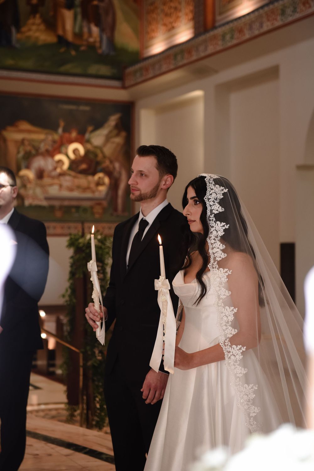 Elegant wedding ceremony in an ornate indoor venue with warm lighting and decorative details.