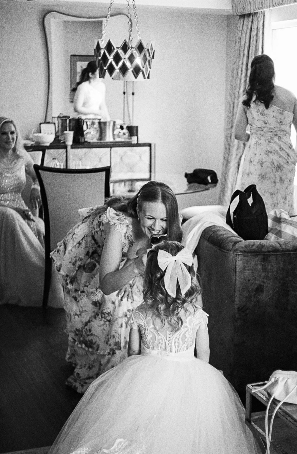 A series of black and white photos showing a bride in an elegant white wedding dress with delicate details and bow accents.